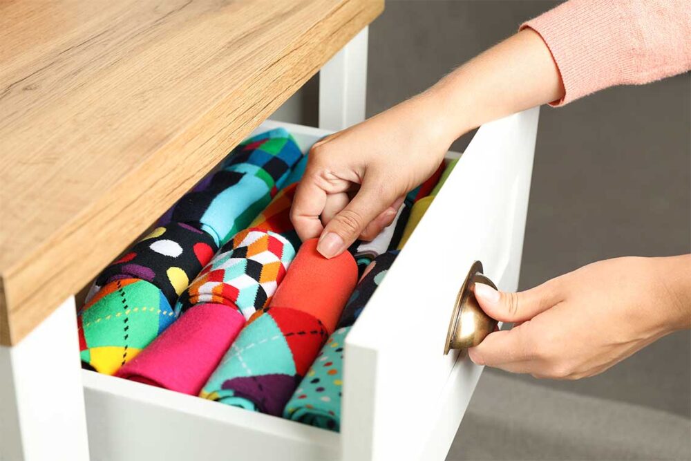 شخصی درحال قرار دان جوراب در کشو کمد