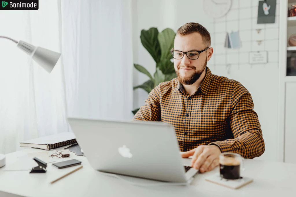 مردی که پیرزاهن چهارخانه پوشیده و درحال کار با لپ تاپ است