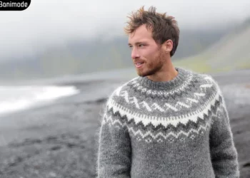 مرد جوانی که در ساحل دریاچه پلیور بافت طوسی سفید پوشیده است.