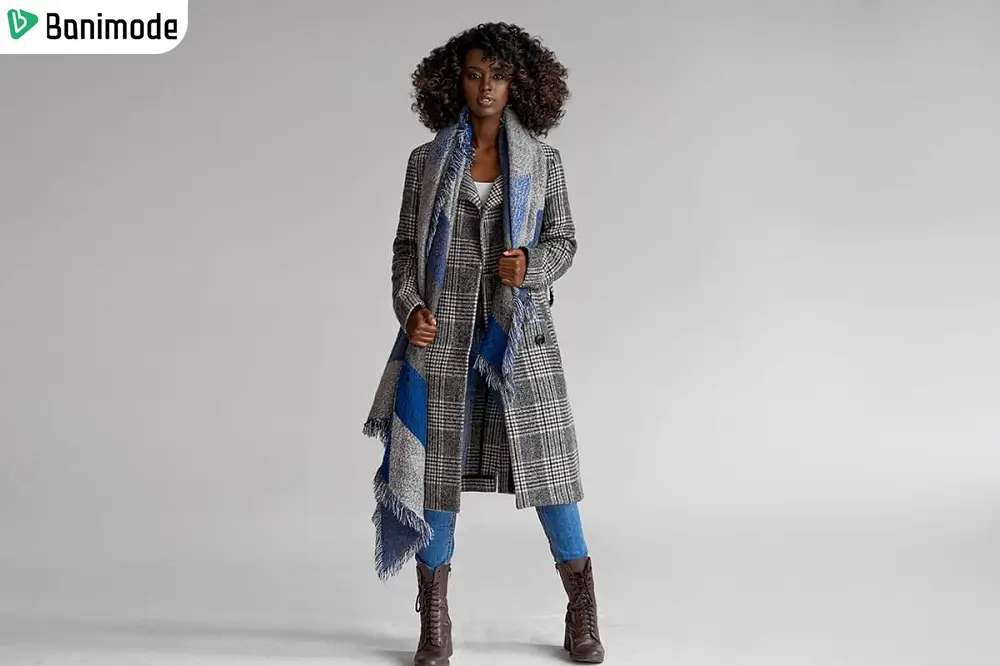 یک خانم مو فرفری که پالتو چهارخانه کلاسیک خاکستری پوشیده