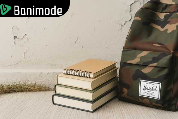 کوله پشتی چریکی روی زمین در کنار کتاب و دفتر